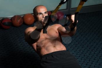 Attractive Man Does Push Ups With Trx Fitness Straps In The Gym's Studio