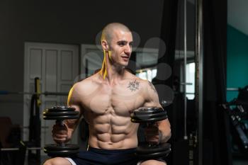 Portrait Of A Physically Fit Young Man In A Healthy Club With Dumbbells