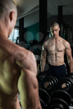 Young Man Working Out Biceps In Front Of A Mirror - Dumbbell Concentration Curls