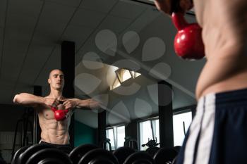Young Man Working With Kettle Bell In Front Of A Mirror