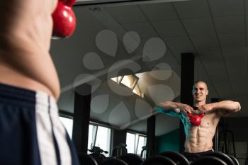 Young Man Working With Kettle Bell In Front Of A Mirror