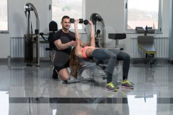 Personal Trainer Showing Young Woman How To Train Chest Exercise With Dumbbells In A Health And Fitness Concept