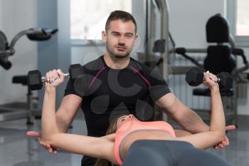 Personal Trainer Showing Young Woman How To Train Chest Exercise With Dumbbells In A Health And Fitness Concept