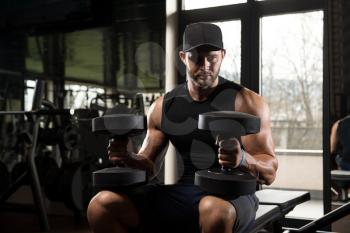 Portrait Of A Physically Fit Young Man In A Healthy Club With Dumbbells