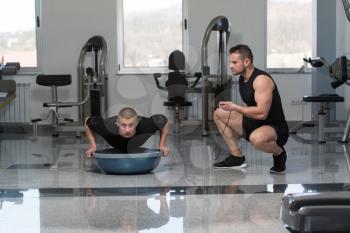 Personal Trainer Showing Young Man How To Train On Bosu Push Ups In A Health And Fitness Concept
