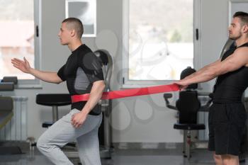Male Couple Train Together With Resistance Bands A Leg Exercise In A Health And Fitness Concept