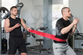 Male Couple Train Together With Resistance Bands A Leg Exercise In A Health And Fitness Concept