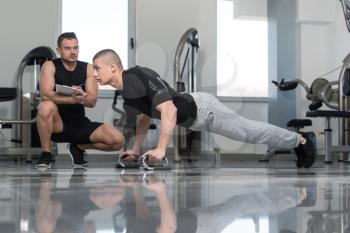 Personal Trainer Showing Young Man How To xercise Push-Up Strength In A Health And Fitness Concept