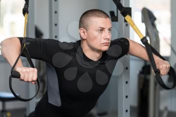 Attractive Young Man Does Crossfit Push Ups With Trx Fitness Straps In The Gym's Studio