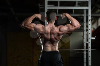 Portrait Of A Young Fit Man Performing Rear Double Biceps Pose - Muscular Athletic Bodybuilder Fitness Model Posing After Exercises