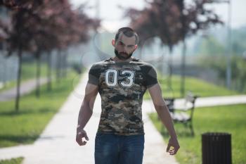Young Man In A Shirt Stands In The Park And Relaxing