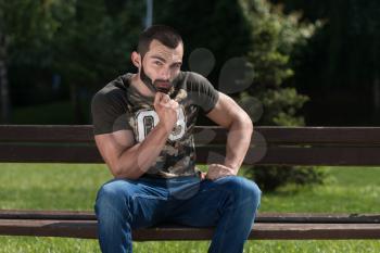 Man In A Shirt Sitting In The Park And Relaxing
