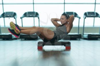 Young Woman Athlete Doing Abs Exercise On Stepper As Part Of Bodybuilding Training
