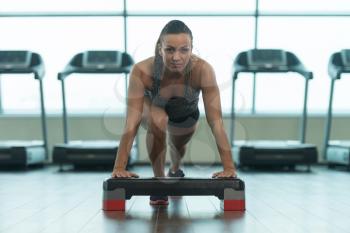 Muscular Woman Stretches At The Floor In A Gym And Flexing Muscles - Muscular Athletic Bodybuilder Fitness Model