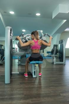 Young Woman Exercising Back On Machine In The Gym And Flexing Muscles - Muscular Athletic Bodybuilder Fitness Model