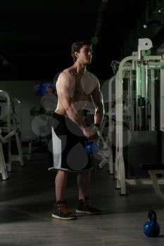 Young Man Working Out With Kettle Bell In A Dark Gym - Bodybuilder Doing Heavy Weight Exercise With Kettle-bell