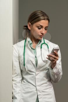 Portrait Of A Young Beautiful Female Doctor Writing Text On Mobile - Healthcare Worker Working Online