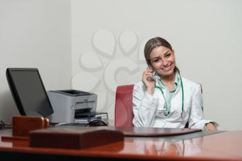 Beautiful Young Female Doctor Woman In office Talking On Cell Phone - Healthcare Worker Working Online