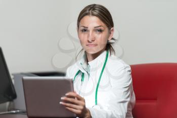 Portrait Of A Young Female Doctor Using Digital Tablet At Office - Healthcare Worker Working Online