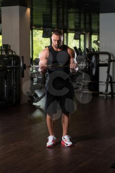 Big Man Standing Strong In The Gym And Exercising Biceps With Barbell - Muscular Athletic Bodybuilder Model Exercise In Fitness Center