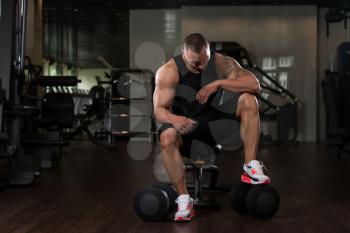 Portrait Of A Muscular Man Resting On The Bench In Fitness Gym