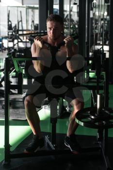 Young Strong Man In The Gym And Exercising Biceps On Machine - Muscular Athletic Bodybuilder Fitness Model Exercise Bicep