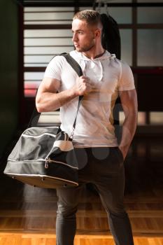Fit young man with gym bag going on the in gym