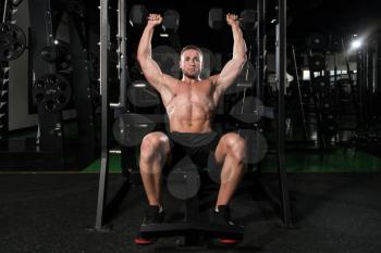 Young Strong Man In The Gym And Exercising Shoulders With Dumbbells - Muscular Athletic Bodybuilder Fitness Model Exercise Shoulder