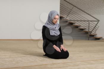 Young Muslim Woman Making Traditional Prayer To God While Wearing A Traditional Hijab And Dress