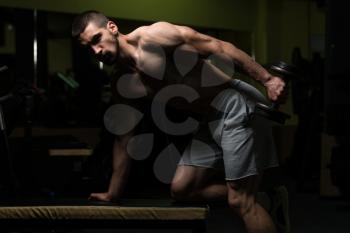 Young Muscular Man Doing Heavy Weight Exercise For Triceps With Dumbbell In Gym