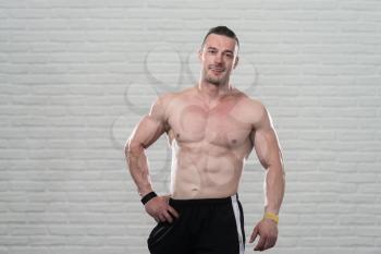 Strong Athletic Man Fitness Model Torso Showing Six Pack Abs - Isolated On White bricks Background With Copyspace