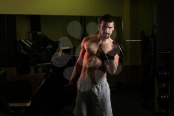 Young Muscular Man Doing Heavy Weight Exercise For Biceps With Dumbbells In Gym