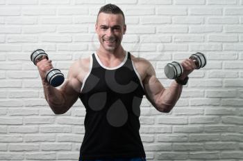 Young Man Working Out Biceps With Dumbbells On White Bricks Background With Copyspace - Dumbbell Concentration Curls