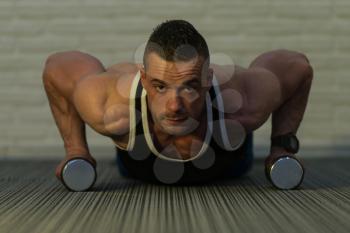 Young Bodybuilder Doing Pushups With Dumbbells As Part Of Bodybuilding Training