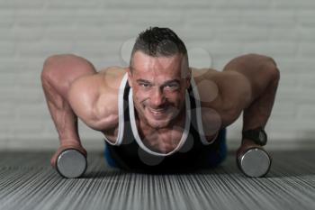 Young Man Doing Pushups With Dumbbells As Part Of Bodybuilding Training