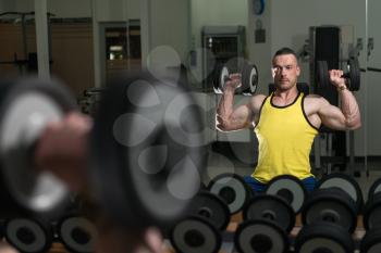 Young Man Working Out Shoulders In A Dark Gym At Mirror - Dumbbell Concentration Curls