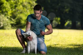 Man Cleans The Dog German Spitz In Park - He Is Going Crazy