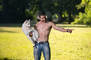 Sexy Young Man Holding Dog German Spitz In Park - Together Enjoying The View