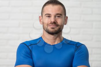 Personal Trainer Standing Strong On White Bricks Background With Copyspace And Flexing Muscles - Muscular Athletic Man Fitness Model Posing