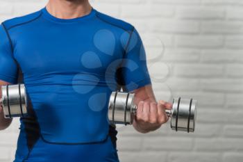 Close Up Personal Trainer Working Out Biceps With Dumbbells On White Bricks Background With Copyspace - Dumbbell Concentration Curls