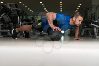 Personal Trainer Doing Pushups With Medicine Ball As Part Of Bodybuilding Training