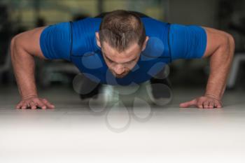 Personal Trainer Doing Pushups On Floor In Gym As Part Of Bodybuilding Training