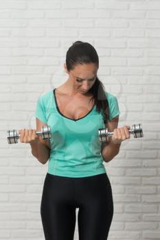 Attractive Woman Working Out Biceps With Dumbbells On White Bricks Background With Copyspace - Dumbbell Concentration Curls