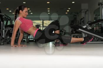 Attractive Woman Exercising With Wheel Roller For Legs On Floor In Gym As Part Of Fitness Training