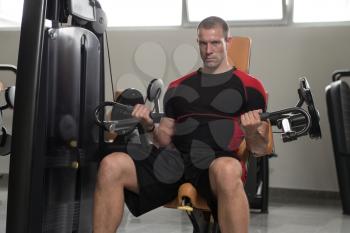 Good Looking And Attractive Man Doing Heavy Weight Exercise For Biceps On Machine