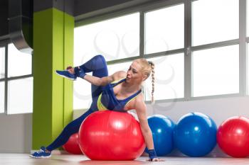 Muscular Woman Stretches On Ball In A Gym And Flexing Muscles - Muscular Athletic Bodybuilder Fitness Model