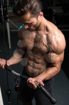 Handsome Muscular Fitness Bodybuilder Doing Heavy Weight Exercise For Biceps On Machine With Cable In The Gym