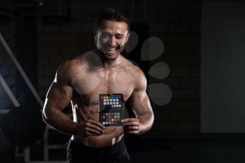 Serious Men Standing In The Gym And Holding A Color Checker Equipment Of Professional Photographer For Adjust And Balance Photograph