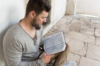 Humble Muslim Man Is Reading The Koran In The Mosque Outdoors