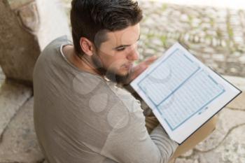 Humble Muslim Man Is Reading The Koran In The Mosque Outdoors